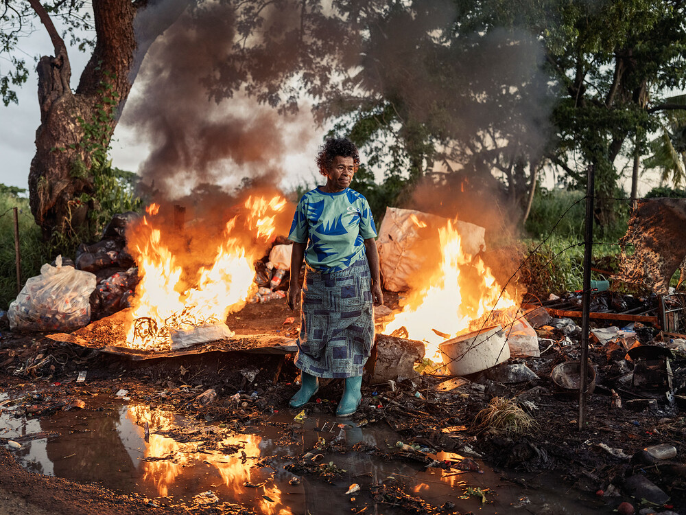 Asinate Lewabeka, a woman who makes an income washing and sorting cans, plastic bottles and other materials for recycling, burns trash near her home in Vunato settlement, Lautoka, on Viti Levu, Fiji on May 9, 2024. Photo by Adam Ferguson for TIME