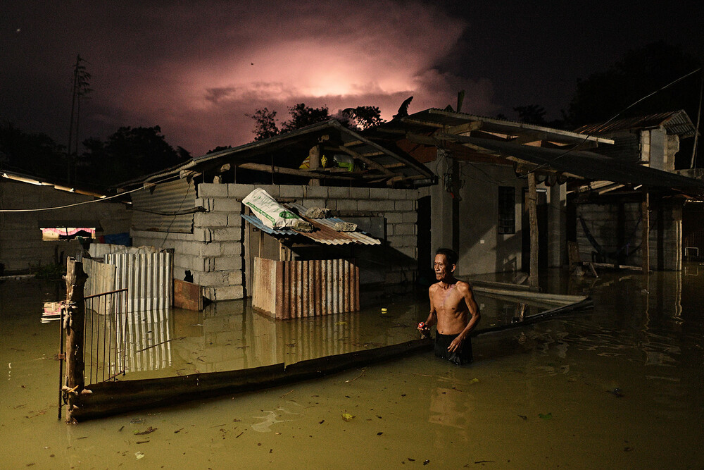 A resident wades through a flooded street caused by heavy rains from typhoon Toraji in Ilagan City, Isabela province, northern Philippines on Tuesday, Nov. 12
