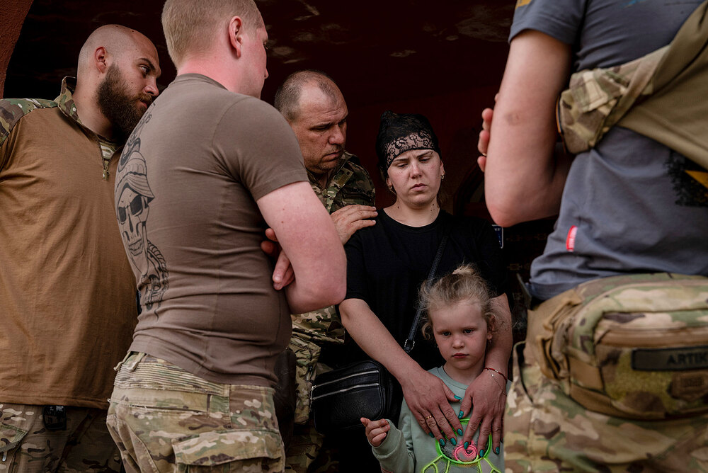 Ukrainian soldiers comforted Iryna Sharhorodska, and her daughter Sonia, following the funeral for her husband Sergeant Oleksandr Sharhorodskyi, on Sunday, May 21, 2023. (Nicole Tung/The New York Times) Ukrainian soldiers comforted Iryna Sharhorodska, and her daughter Sonia, following the funeral for her husband Sergeant Oleksandr Sharhorodskyi, on Sunday, May 21, 2023. (Nicole Tung/The New York Times)