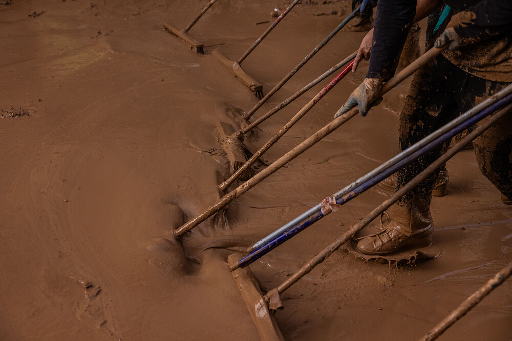 Volunteers work on Friday Nov. 1, 2024, to remove mud from the center of Paiporta, considered the ground zero of the devastating floods in the province of Valencia, Spain. Thousands of volunteers came from all over to help residents clean homes, businesses and streets, as well as completing other essential tasks in the days following the catastrophe on October 29. Santi Palacios for El País