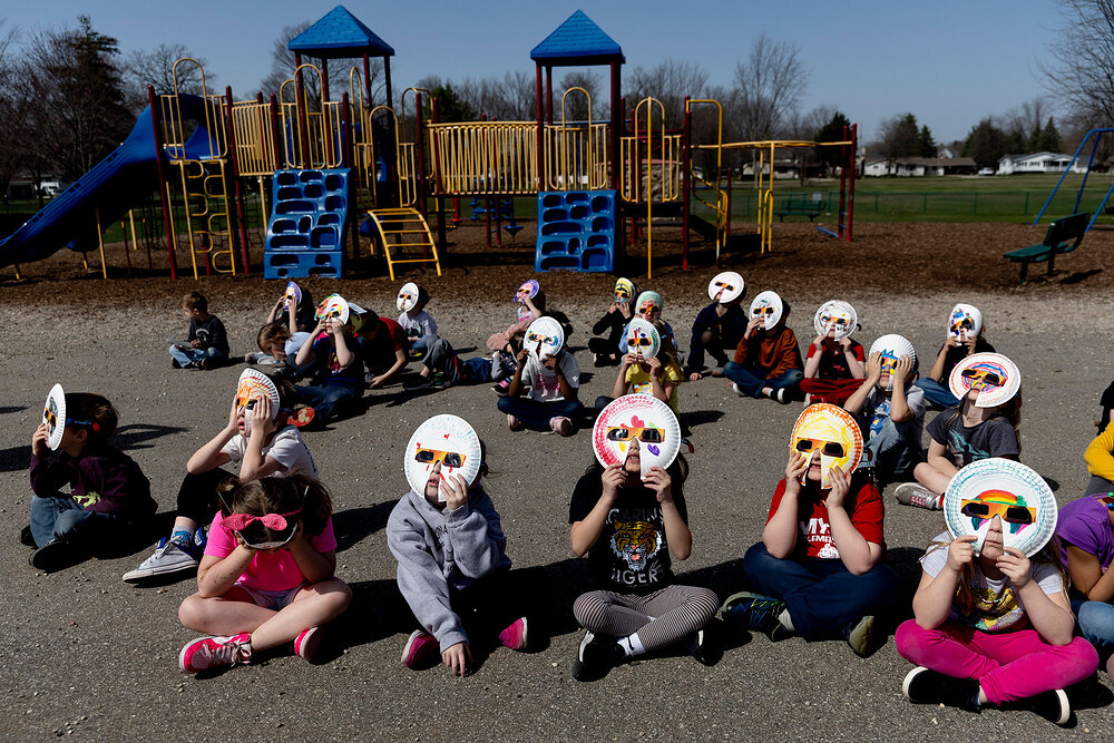 Kindergartners at Myers Elementary School in Grand Blanc, Mich., use paper-plate glasses to safely watch the solar eclipse on April 8.